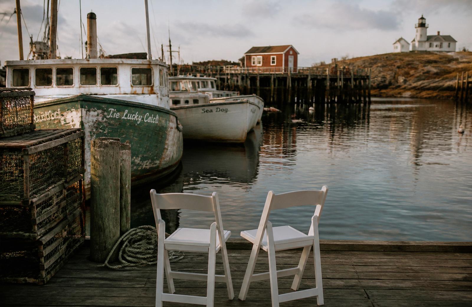 White lighthouse and ceremony chairs on a Maine rocky headland at golden hour.